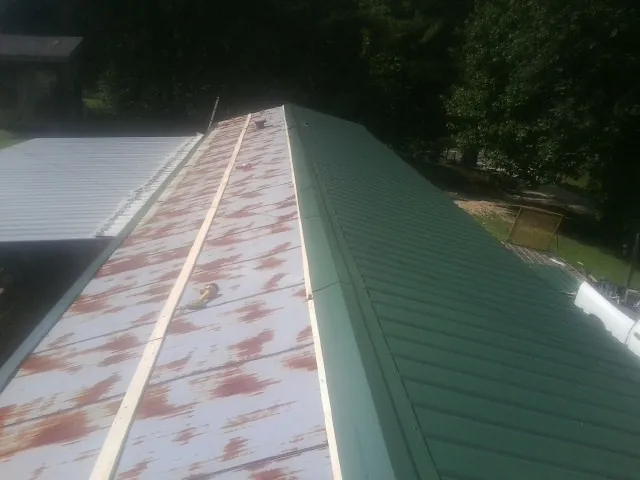 Old rusted panels beside newly installed green metal roofing — Wind Damage Roof Repair by Roofing Brothers in Woodland